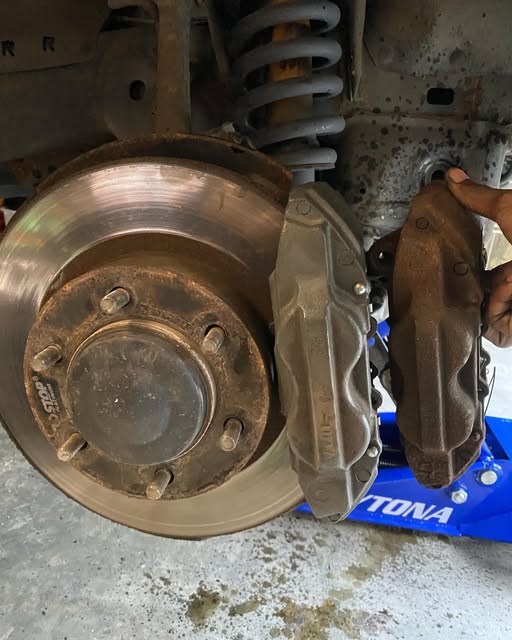 A worn brake rotor and suspension spring exposed during a brake job.