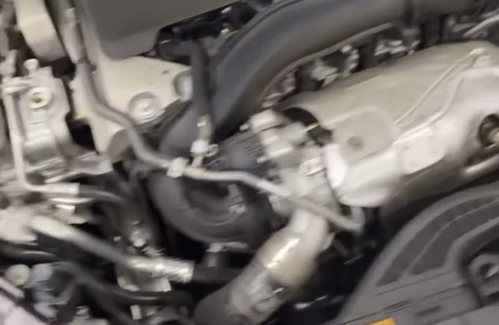 An engine bay with the cover off, hoses and coolant pipes visible during diagnosis.