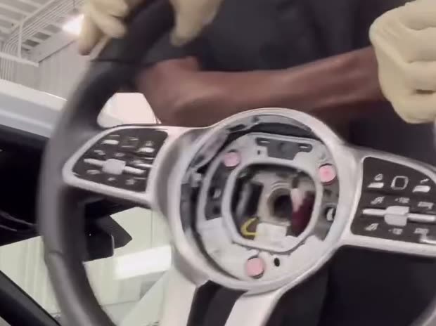 Gloved hands holding a steering wheel removed from a vehicle